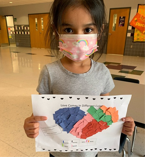 Little girl holding up her artwork