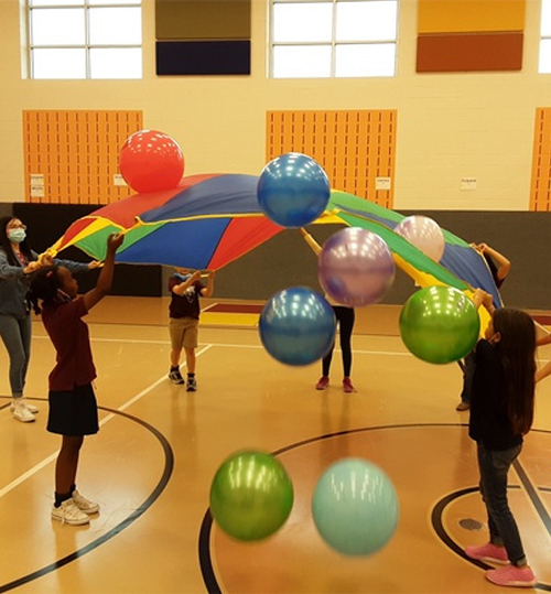 group of students in gym doing an experiment with balloons